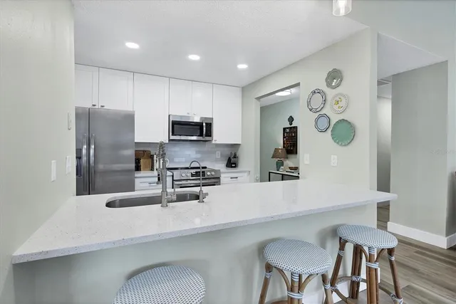 a kitchen with stainless steel appliances a dining table chairs refrigerator and microwave