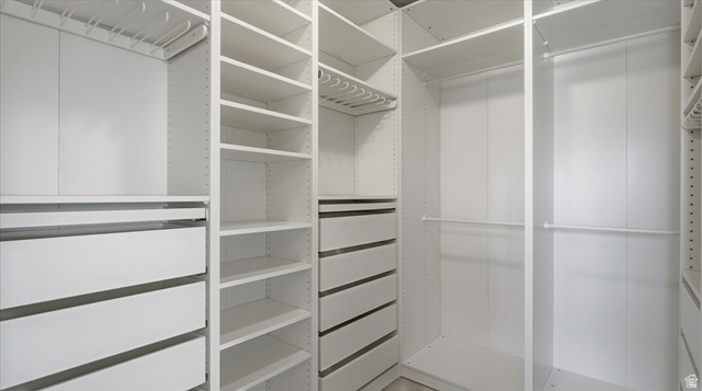 2038 East Ranch Road Eagle Mountain, UT 84005 - Photo 23 of 66 Custom closet system featuring white cabinetry, multiple hanging rods, integrated drawers, extensive shelving, and slide-out storage