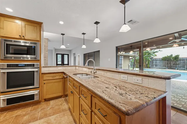 a kitchen with stainless steel appliances granite countertop a refrigerator a oven and a sink
