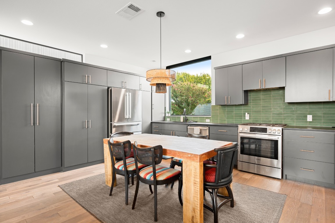 a kitchen with stainless steel appliances granite countertop a table chairs stove and refrigerator