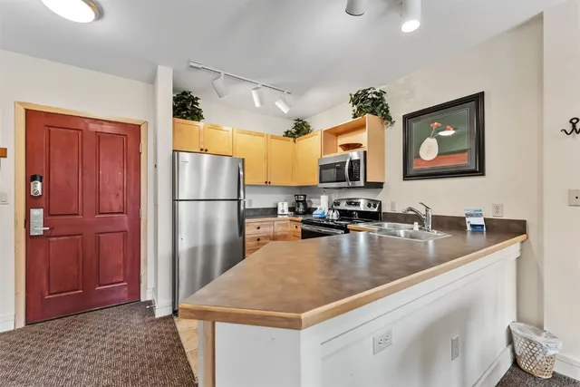 a kitchen with stainless steel appliances granite countertop a refrigerator a stove and a sink with wooden floor