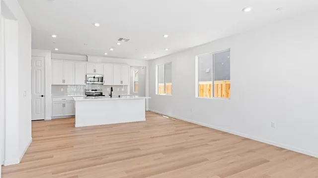 a view of kitchen with kitchen island wooden floor center island and stainless steel appliances