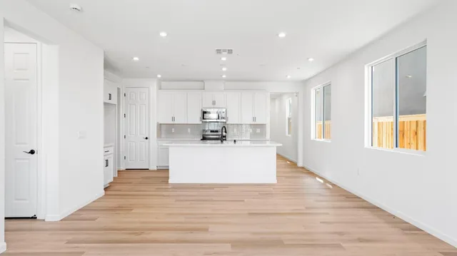a view of kitchen with kitchen island a sink wooden floor and a refrigerator
