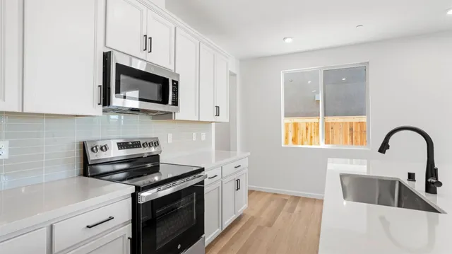 a kitchen with stainless steel appliances granite countertop white cabinets a microwave oven and a sink