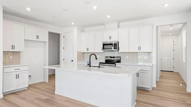 a kitchen with kitchen island a white counter top space a stove and cabinets