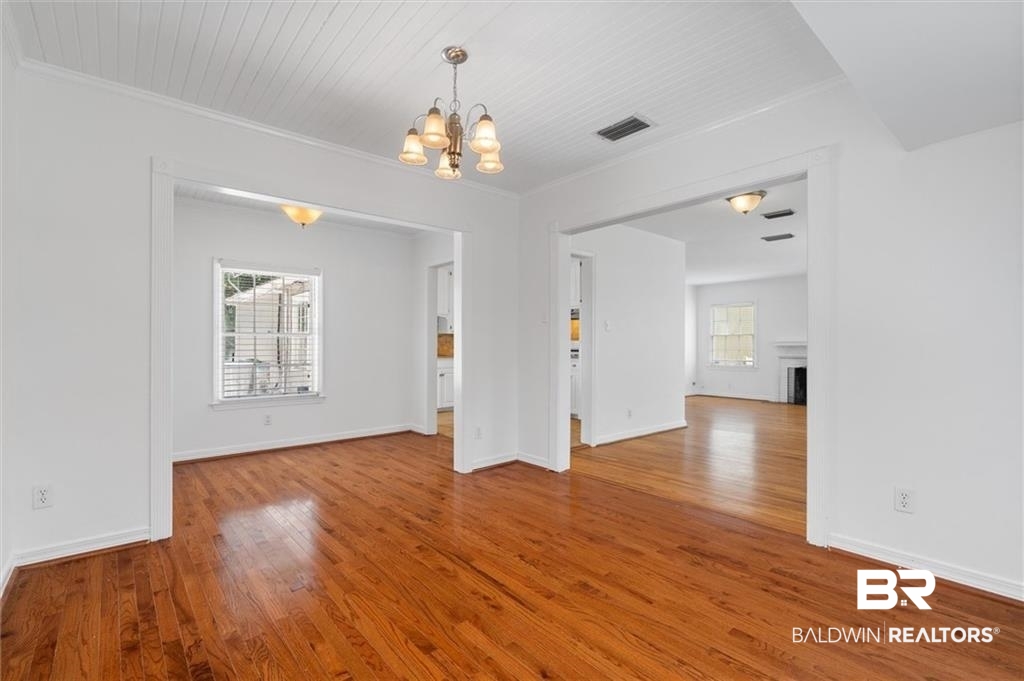 218 Grand Boulevard Mobile, AL 36607 - Photo 18 of 22 Unfurnished room featuring a wealth of natural light, an inviting chandelier, and wood-type flooring