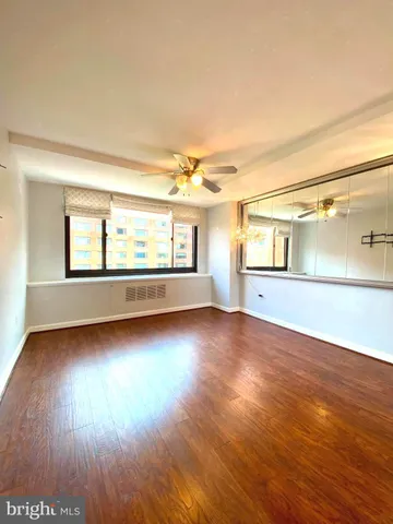 a view of empty room with wooden floor and fan