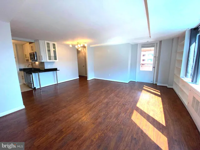 a view of empty room and kitchen with wooden floor
