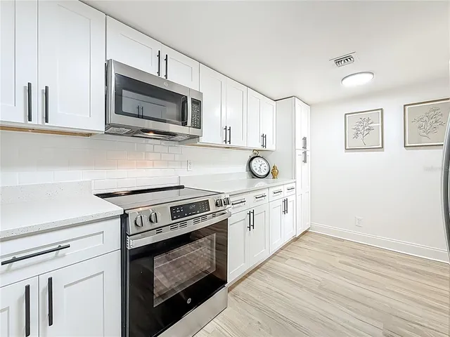 a kitchen with stainless steel appliances white cabinets and stove top oven