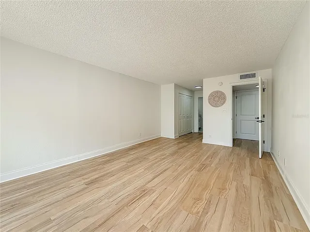 a view of a hallway with wooden floor and a bathroom