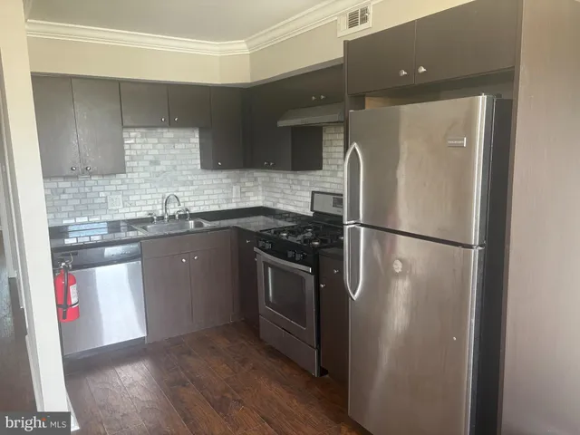 a kitchen with stainless steel appliances granite countertop a refrigerator a sink and white cabinets