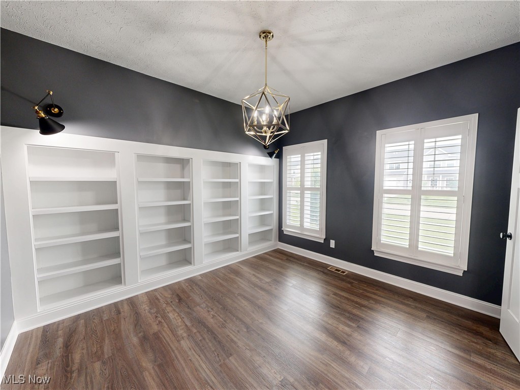 37328 Sandy Ridge Drive North Ridgeville, OH 44039 - Photo 17 of 39 Spare room featuring a chandelier, dark wood-type flooring, a textured ceiling, baseboards, and built in features