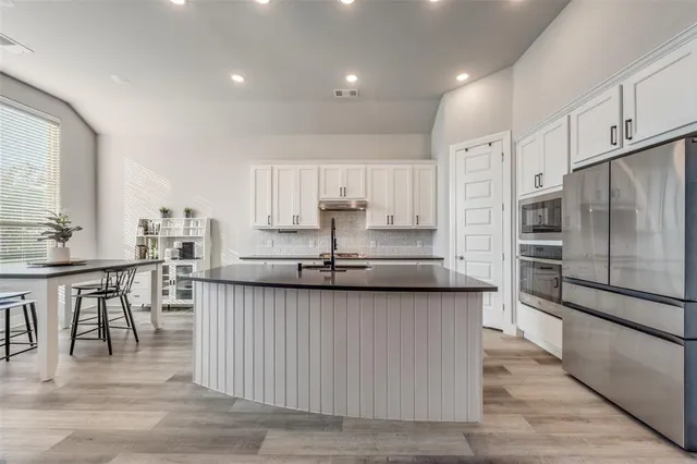 a large kitchen with granite countertop a large counter top stainless steel appliances and cabinets