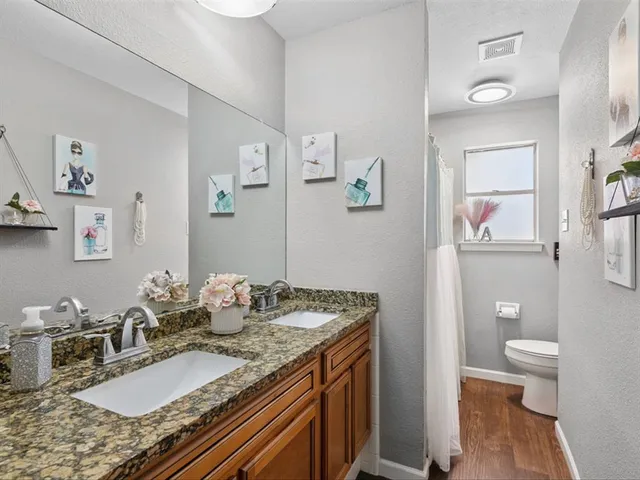 a bathroom with a granite countertop sink a toilet and a mirror