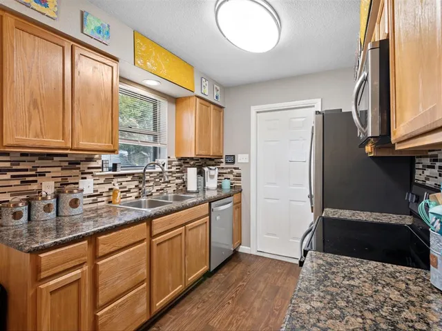 a kitchen with stainless steel appliances granite countertop a stove a sink and a refrigerator with wooden floor