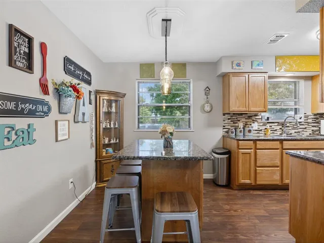 a view of kitchen with stainless steel appliances granite countertop a stove a refrigerator a dining table and chairs with wooden floor