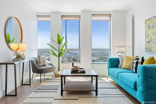 a living room with furniture a rug a potted plant and a window