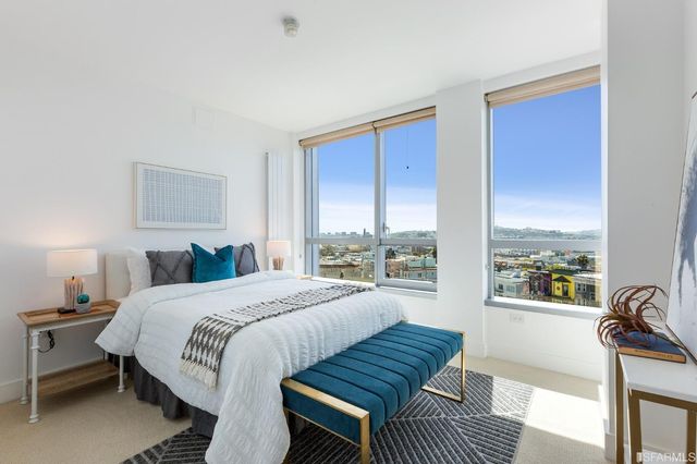 a spacious bedroom with a bed a couch and a large window