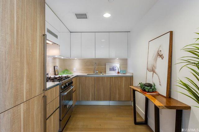 a kitchen with stainless steel appliances granite countertop a refrigerator a sink a stove and white cabinets