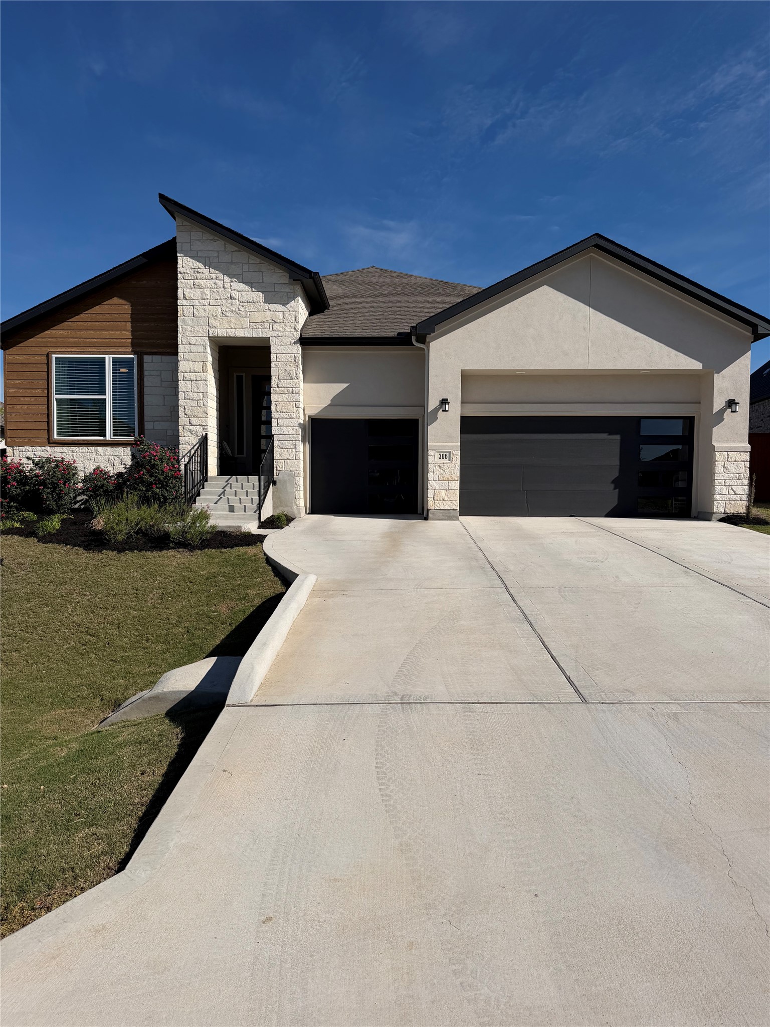 306 Bridge Water Loop Dripping Springs, TX 78620 - Photo 1 of 5 View of front of home featuring stone siding, a garage, driveway, and a front yard