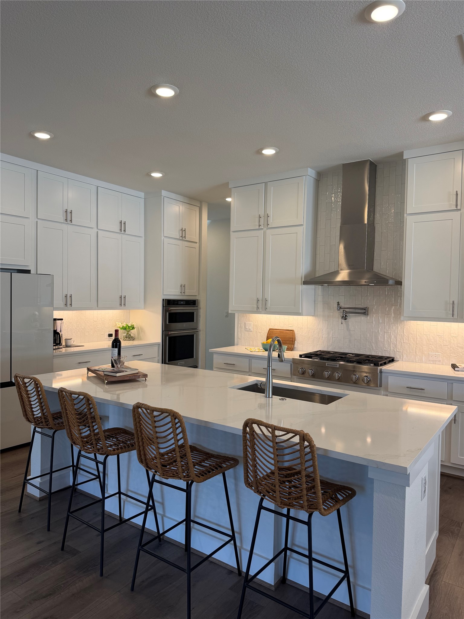 306 Bridge Water Loop Dripping Springs, TX 78620 - Photo 3 of 5 Kitchen with dark wood finished floors, a breakfast bar, white cabinets, stainless steel appliances, and recessed lighting