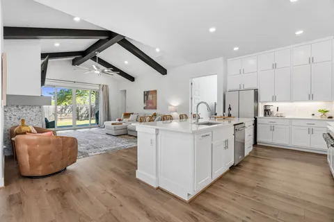 a large white kitchen with cabinets a sink a window and stainless steel appliances