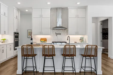 a kitchen with stainless steel appliances granite countertop a table chairs stove and white cabinets
