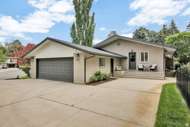 1350 Canyon Park Road Bountiful, UT 84010 - Photo 34 of 38 Brick exterior residence featuring an attached two-car garage with a dark gray door, a concrete driveway, and a front entry with steps