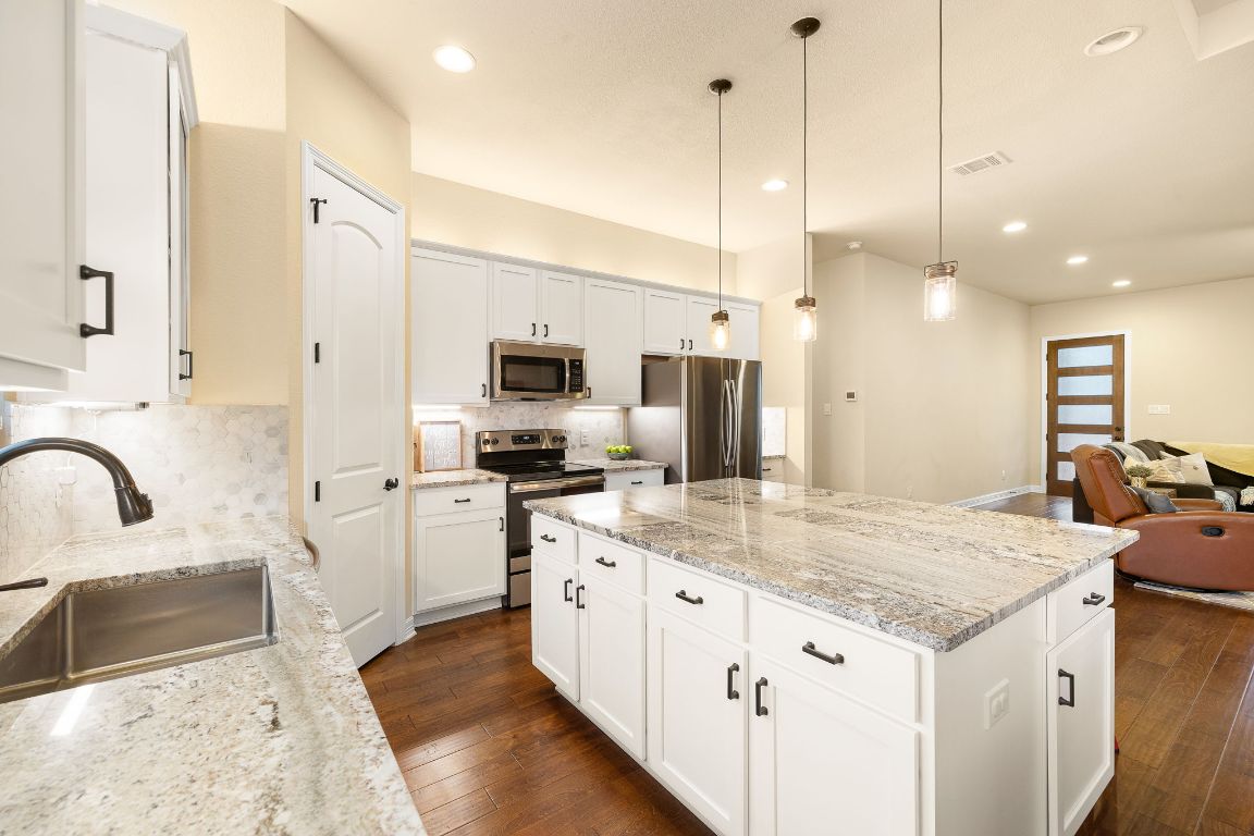 103 Kendall Road Spicewood, TX 78669 - Photo 11 of 37 a kitchen with granite countertop a sink a counter top space appliances and cabinets