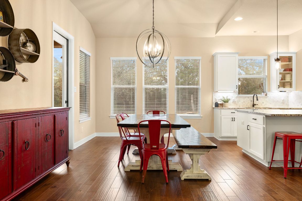 103 Kendall Road Spicewood, TX 78669 - Photo 13 of 37 a dining room with wooden floor a chandelier a wooden table and chairs