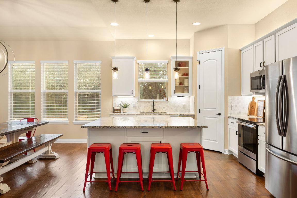 103 Kendall Road Spicewood, TX 78669 - Photo 8 of 37 a kitchen with stainless steel appliances granite countertop a dining table chairs refrigerator and sink