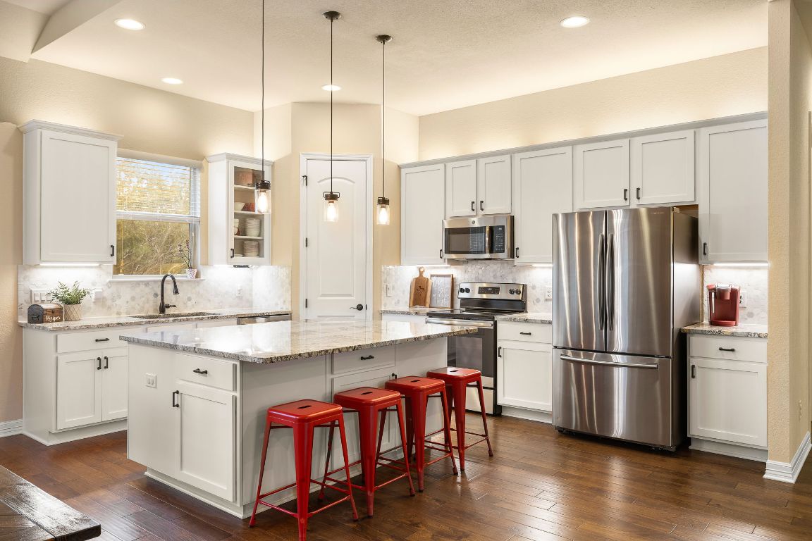 103 Kendall Road Spicewood, TX 78669 - Photo 9 of 37 a kitchen with stainless steel appliances granite countertop a refrigerator a sink and white cabinets