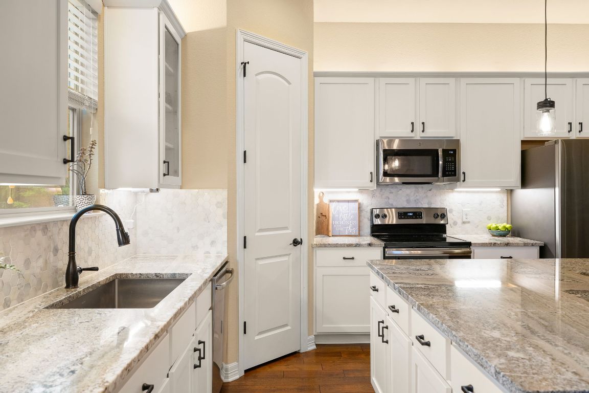 103 Kendall Road Spicewood, TX 78669 - Photo 10 of 37 a kitchen with stainless steel appliances granite countertop a sink a stove top oven a counter space and cabinets