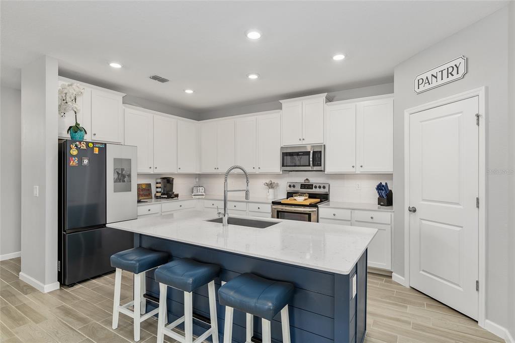 5688 Southwest 92nd Place Ocala, FL 34476 - Photo 18 of 54 a kitchen with stainless steel appliances a sink a stove a refrigerator cabinets and wooden floor