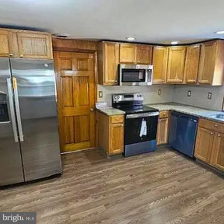 a kitchen with stainless steel appliances granite countertop a stove top oven a refrigerator and cabinets