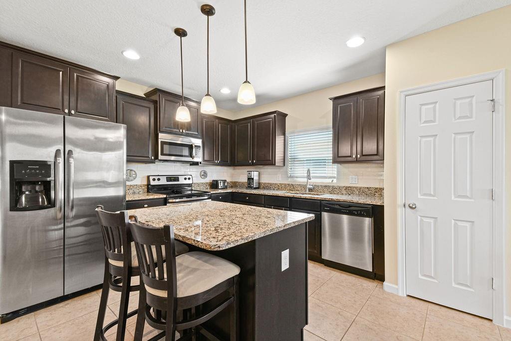 1728 Berkshire Circle Southwest Vero Beach, FL 32968 - Photo 14 of 36 a kitchen with stainless steel appliances granite countertop a stove a sink a microwave a refrigerator and chairs