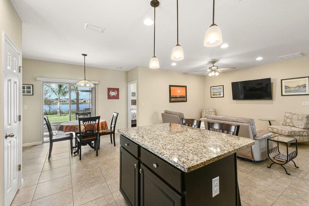 1728 Berkshire Circle Southwest Vero Beach, FL 32968 - Photo 16 of 36 a kitchen with a stove a kitchen island a dining table and chairs with wooden floor
