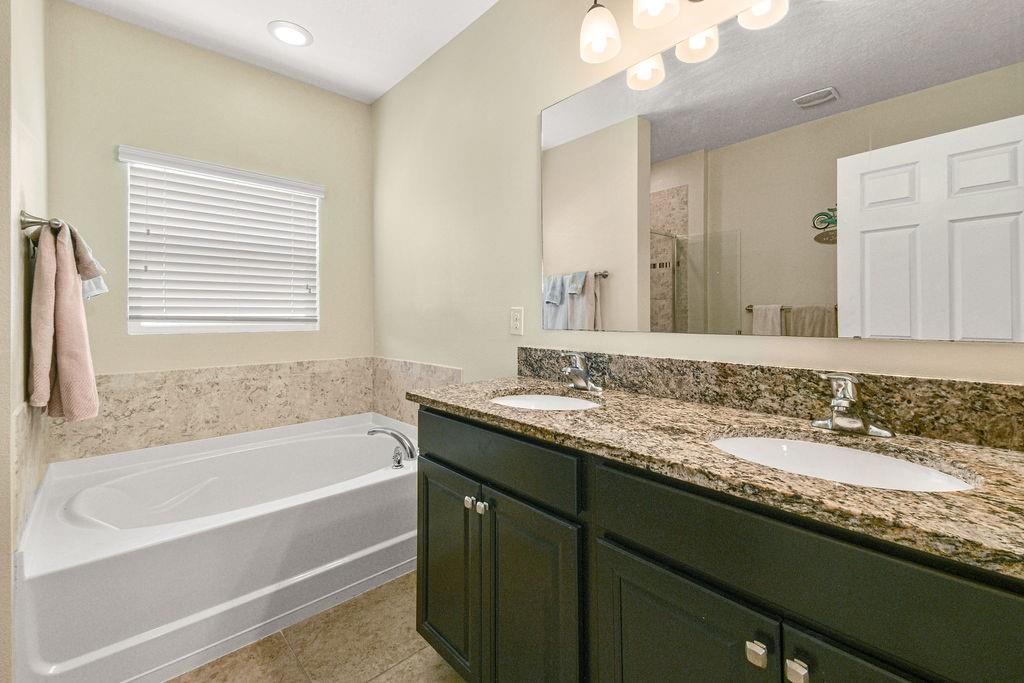 1728 Berkshire Circle Southwest Vero Beach, FL 32968 - Photo 20 of 36 a bathroom with a granite countertop sink mirror and a bathtub