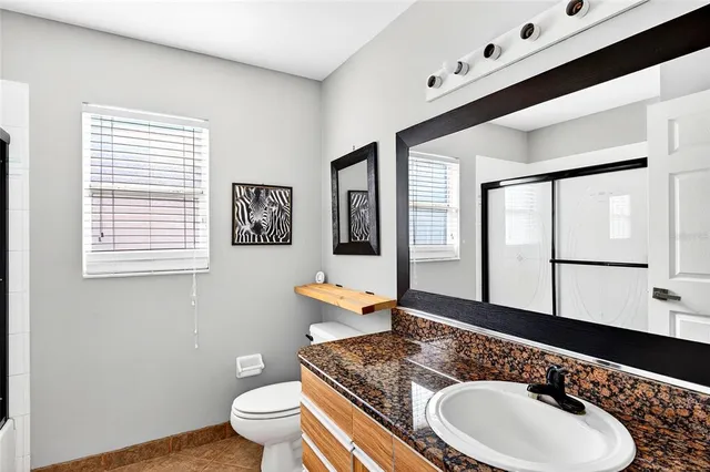 a bath room with a toilet a sink and a large mirror