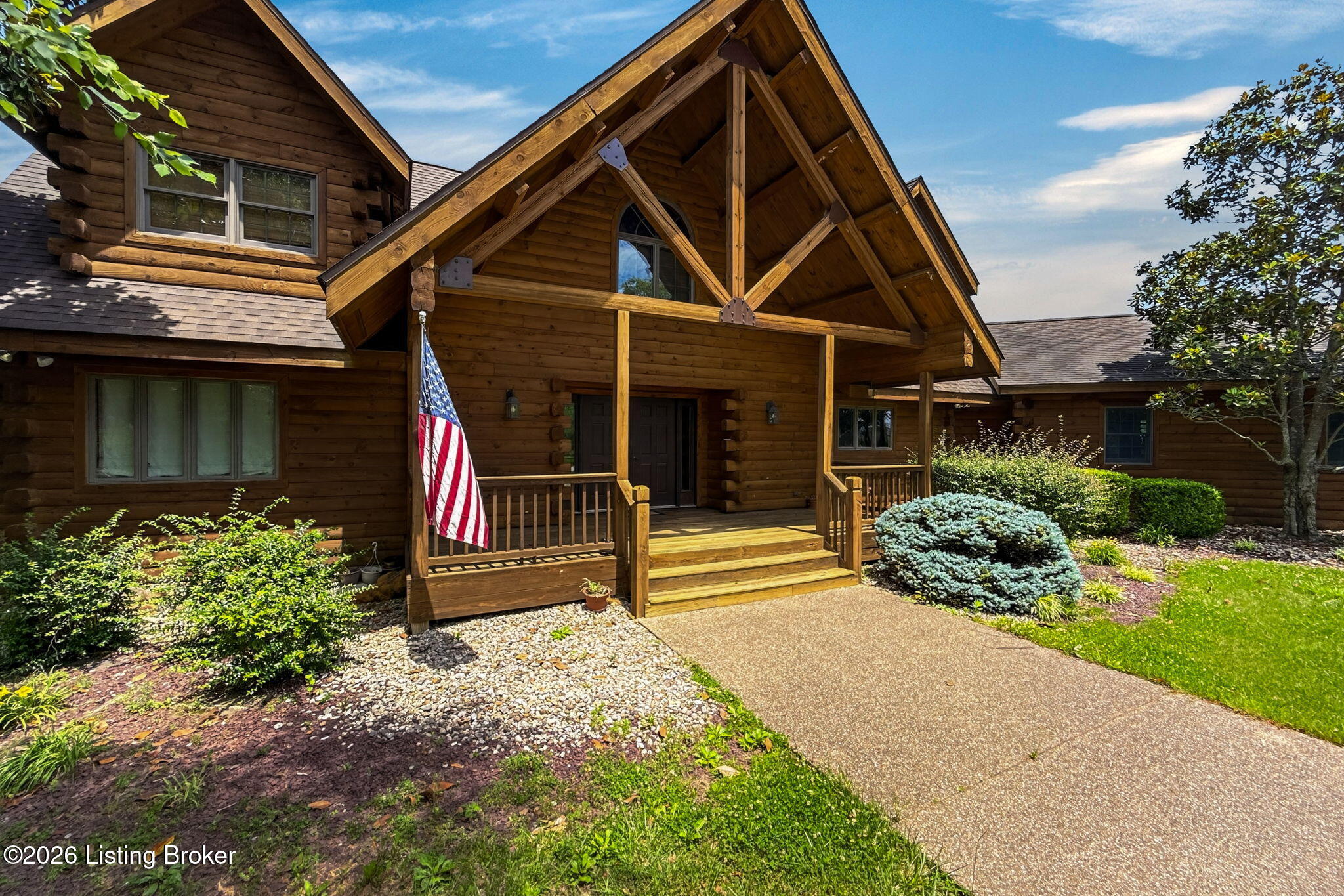 771 Mud Splash Road Elizabethtown, KY 42701 - Photo 18 of 85 Close-up of the covered front porch entry featuring exposed timber framing with decorative copper bracket details, stacked log corners, and a dark wood double front door