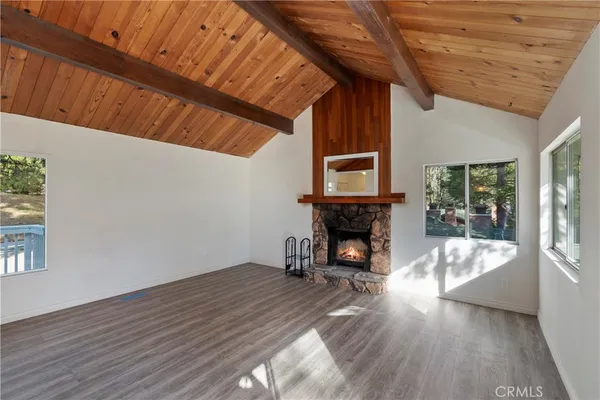 a view of an empty room with wooden floor fireplace and a window