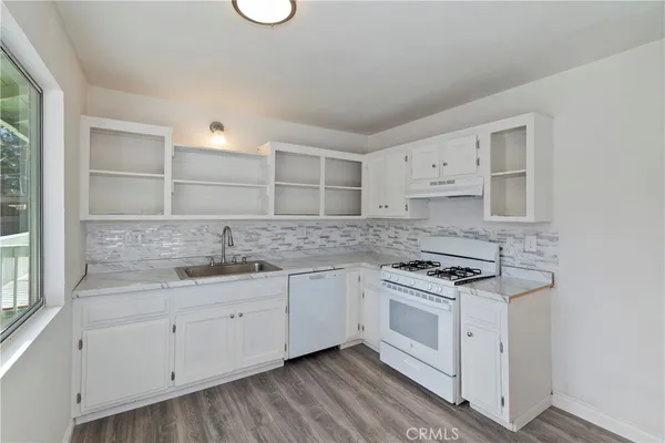 a kitchen with granite countertop white cabinets and white appliances