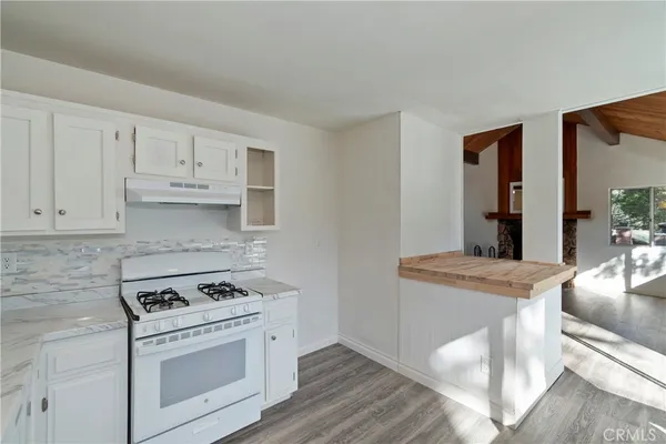 a kitchen with granite countertop a stove and white cabinets