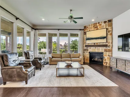 a living room with fireplace furniture large windows and wooden floor