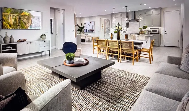 a living room kitchen with stainless steel appliances furniture a rug and a view of kitchen