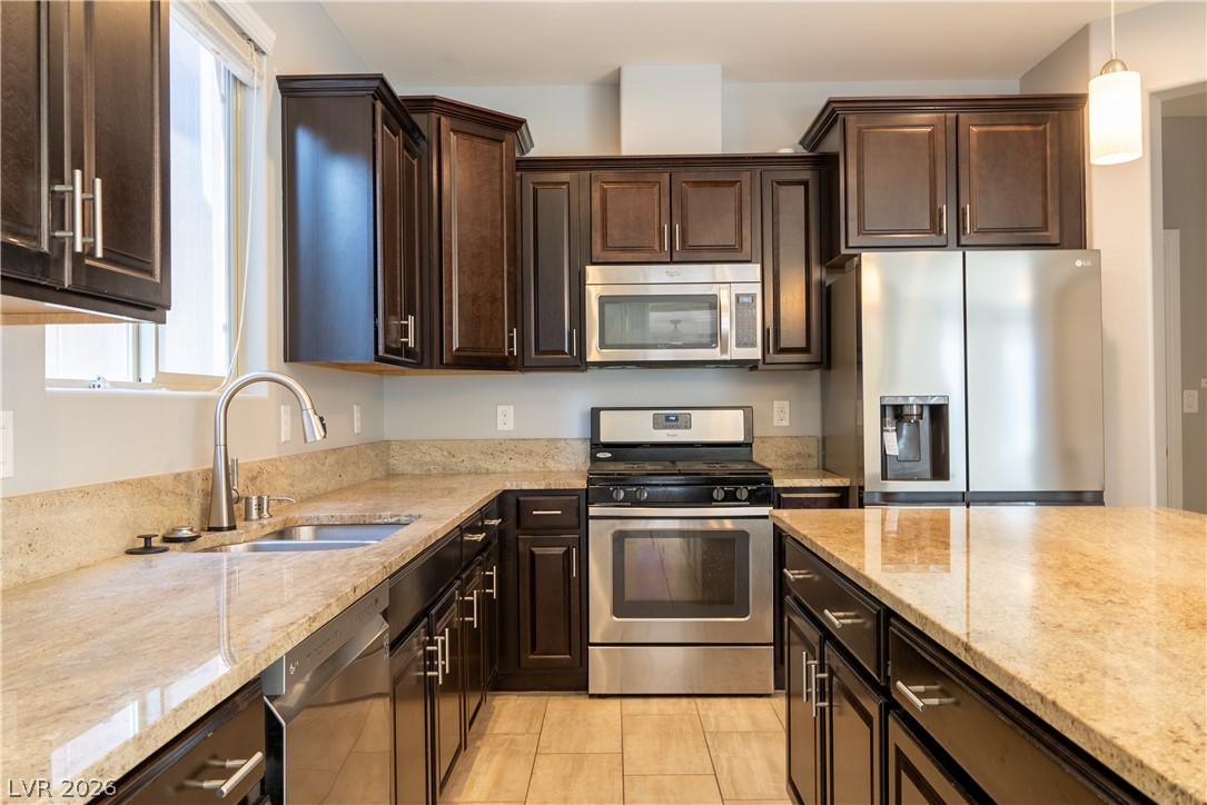 11045 Elk Sands Road Las Vegas, NV 89179 - Photo 15 of 67 Rich dark wood cabinets pair beautifully with polished granite countertops and modern stainless steel appliances.