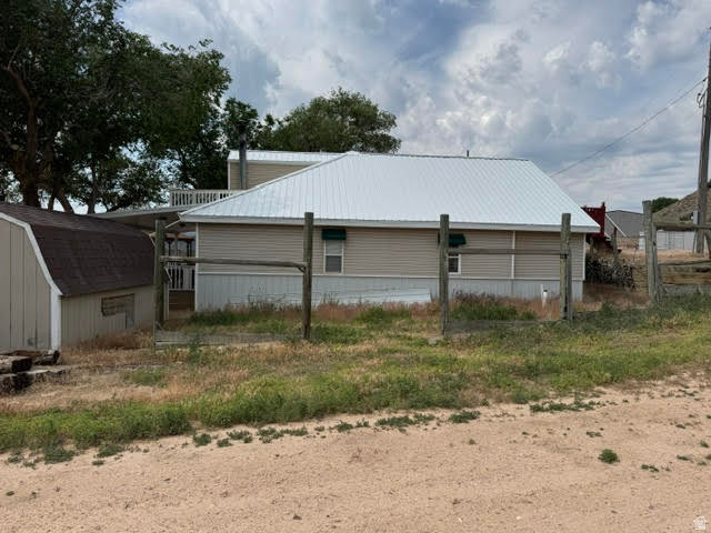 1124 Washam Road Green River, WY 82938 - Photo 5 of 35 Property featuring horizontal panel siding, a light-colored metal roof, and a visible shed with a dark shingle roof