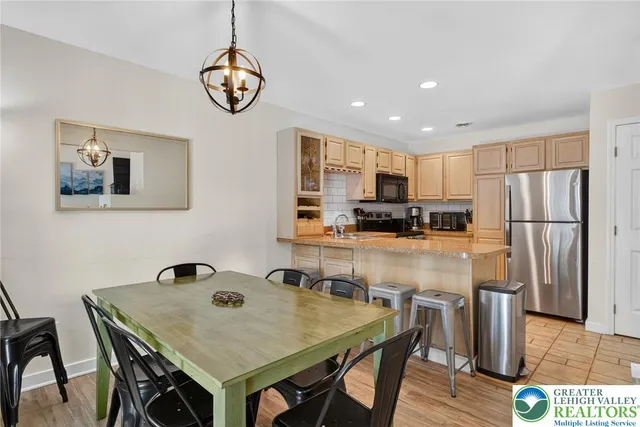 a kitchen with stainless steel appliances granite countertop a dining table chairs refrigerator and microwave
