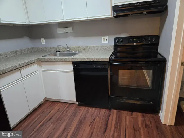 a kitchen with a sink and wooden floor