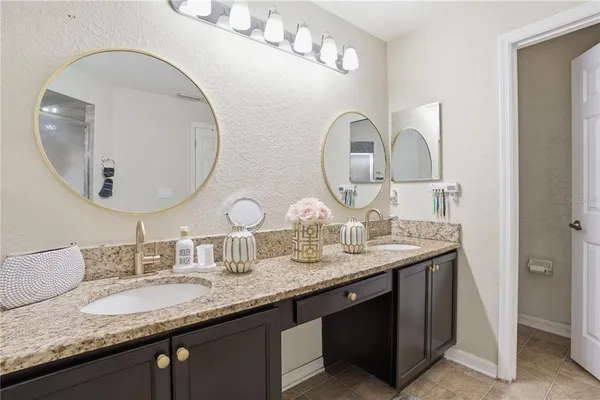 a bathroom with a granite countertop double vanity and a mirror